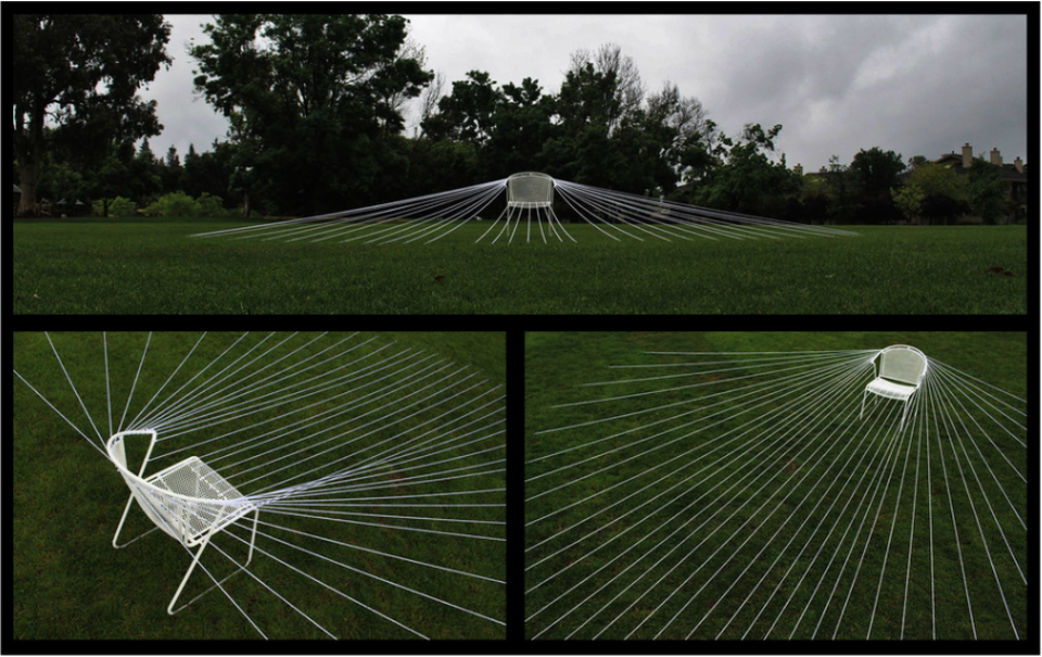 A white chair on a lawn, strung to the ground with dozens of taut white lines