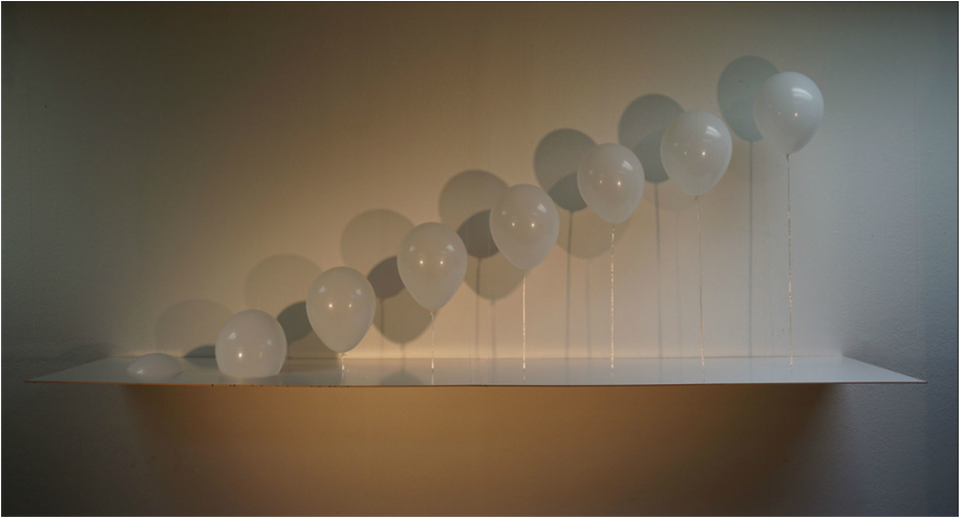 A row of white balloons rising along a shelf